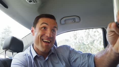Man-taking-a-selfie-on-mobile-phone-in-the-car