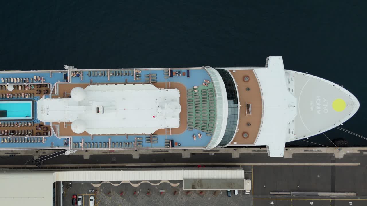 Top down aerial view large white cruise ship docked at port. Sun loungers, pool area and decks