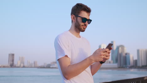 The-man-dials-the-number-on-the-phone-and-talks-on-the-background-of-the-panorama-of-Dubai.-Hand-close-up