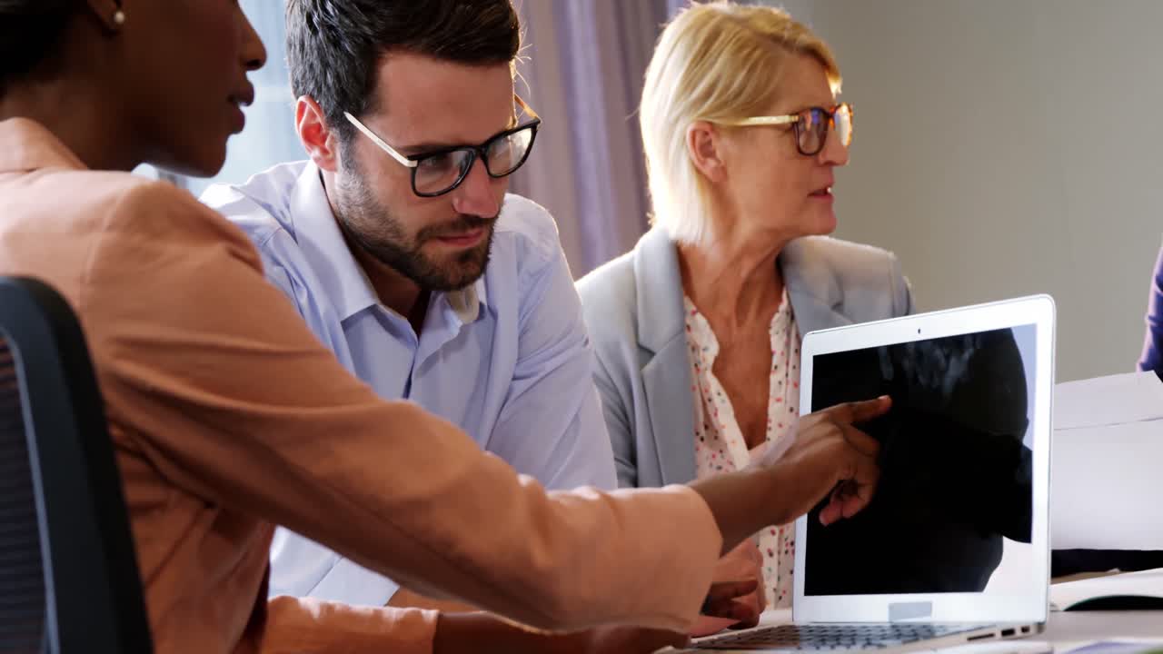 Businesspeople interacting over a laptop