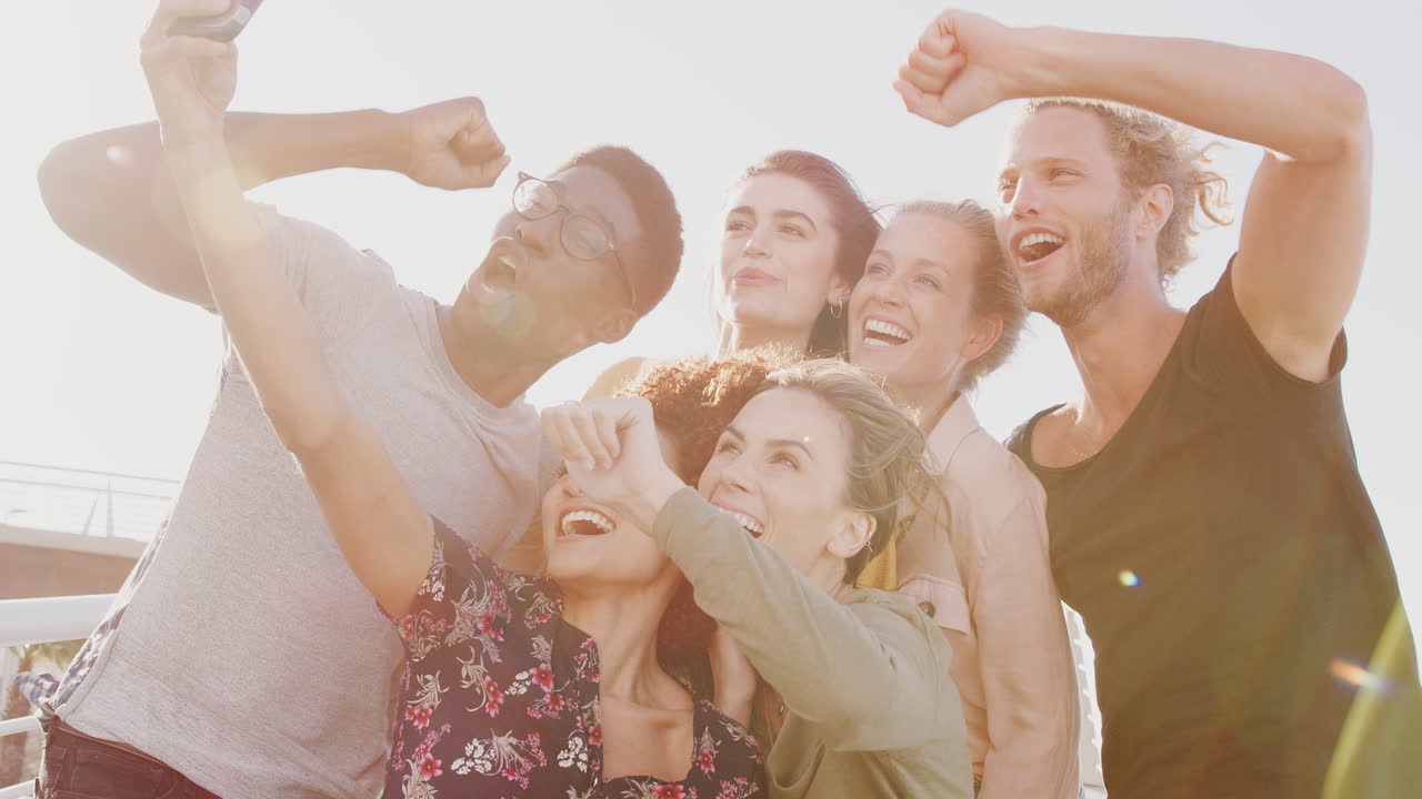 웃는 젊은 친구 들 이 함께 야외 보행자 다리 에서 셀피 를 찍기 위해 포즈 를 취 하고 있다