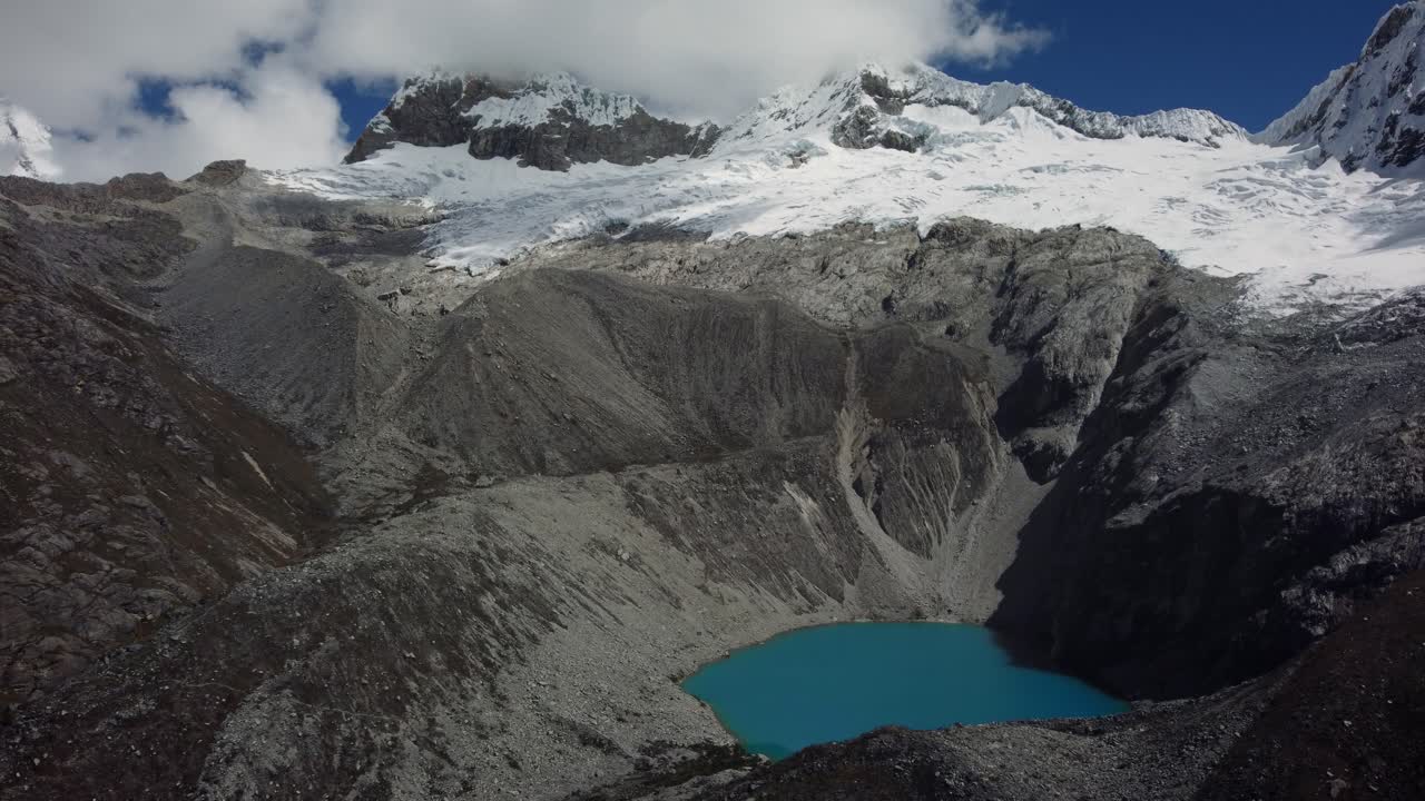 toma aérea con un glaciar congelado y un lago azul con montañas rocosas en la laguna 69 en los andes, perú