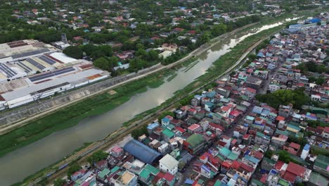 settlements and industrial buildings along the river in marikina, metro manila, philippines. aerial drone shot