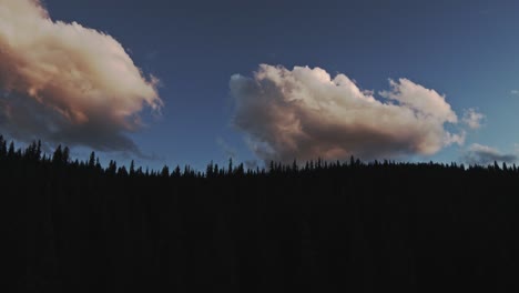 las nubes se forman y se mueven sobre la ladera de una montaña silueteada