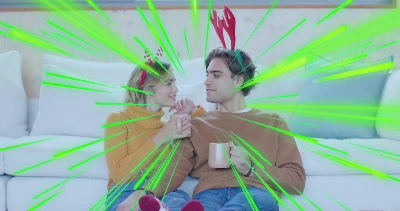 Exchanging glance, couple reaching for headbands and cupping mugs, highlighting holiday marketing