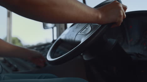 closeup man hand holding steering wheel. driver pushing button on control panel.