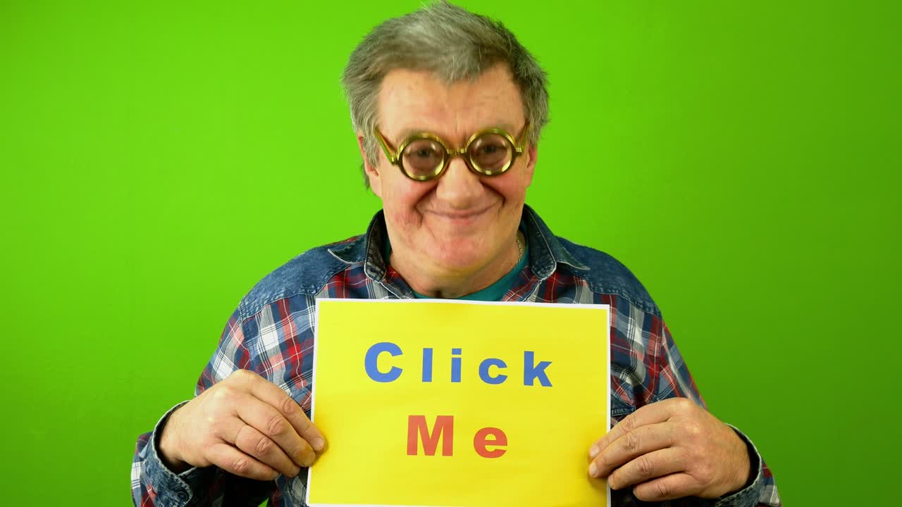 Caucasian mature adult man in fool glasses smiling and point finger at plaque lettering click me.