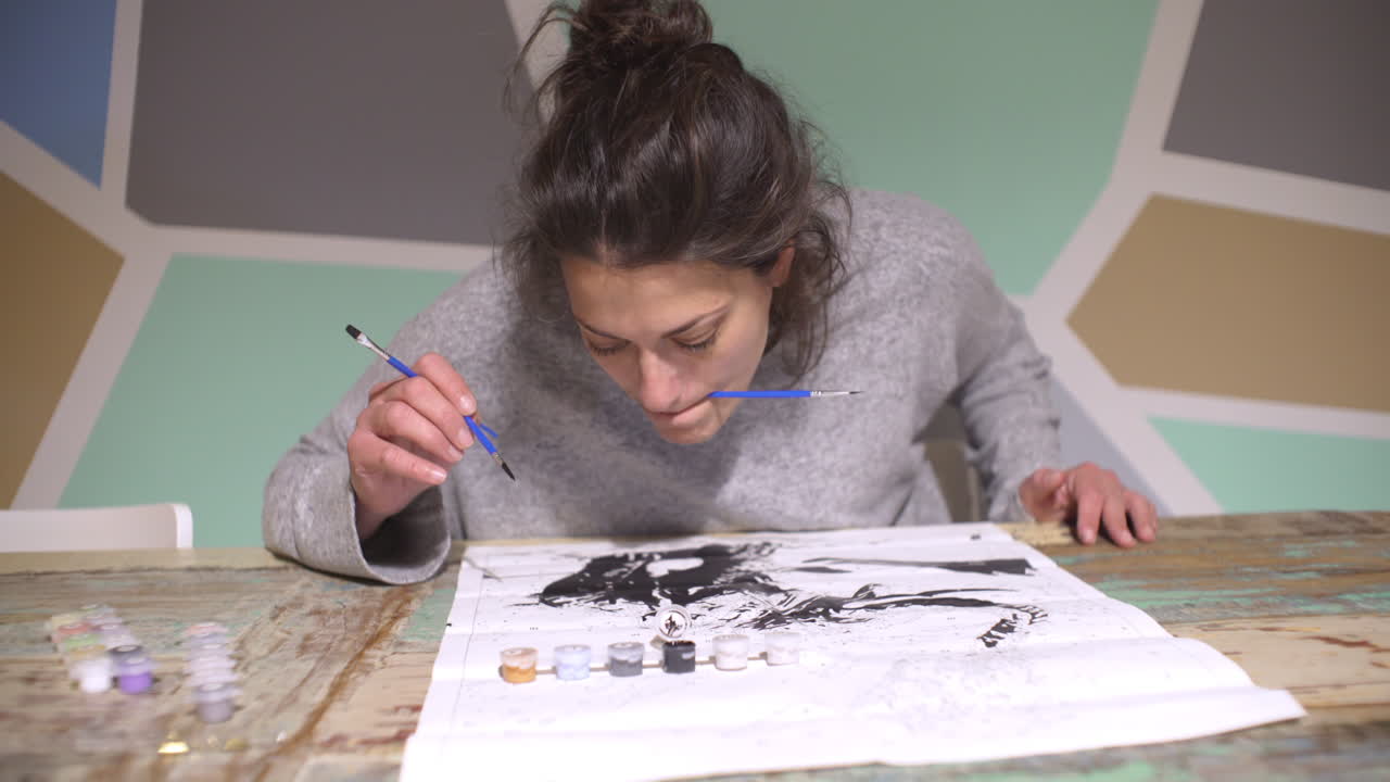 mulher caucasiana pintando em tela branca, pintando pelo método de números 4k, vista frontal push in shot, com parede pastel abstrata no fundo