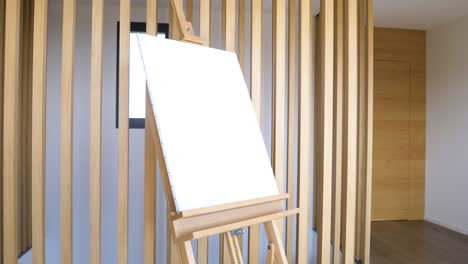 slow rotating shot of a blank canvas standing on a wooden easel in a studio