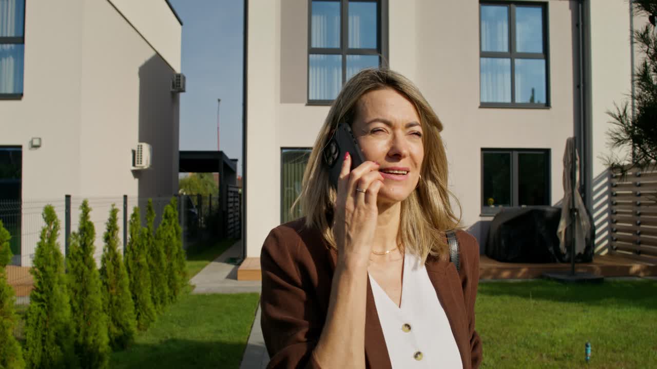 Woman Talking on Phone Outside Modern Home