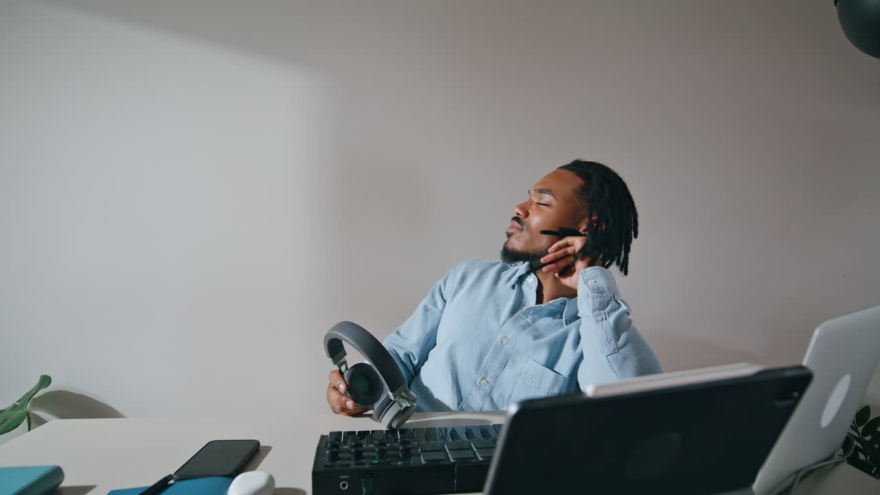 Freelance guy taking headphones off apartment closeup. Tired arranger relaxing
