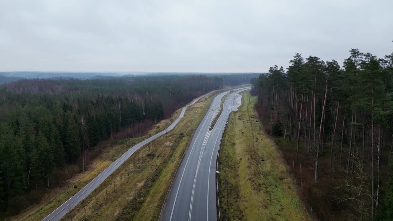 дронный вид двухполосной дороги у леса. движение на дороге в мрачный осенний день