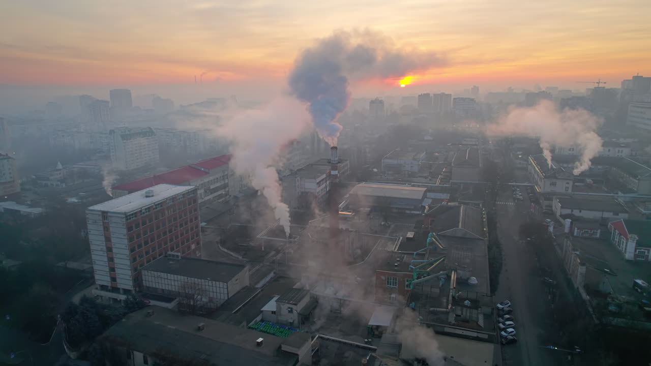 Aerial drone view of an production facility in Chisinau at sunrise, Moldova. Cityscape with multiple buildings, pipes with felling steam