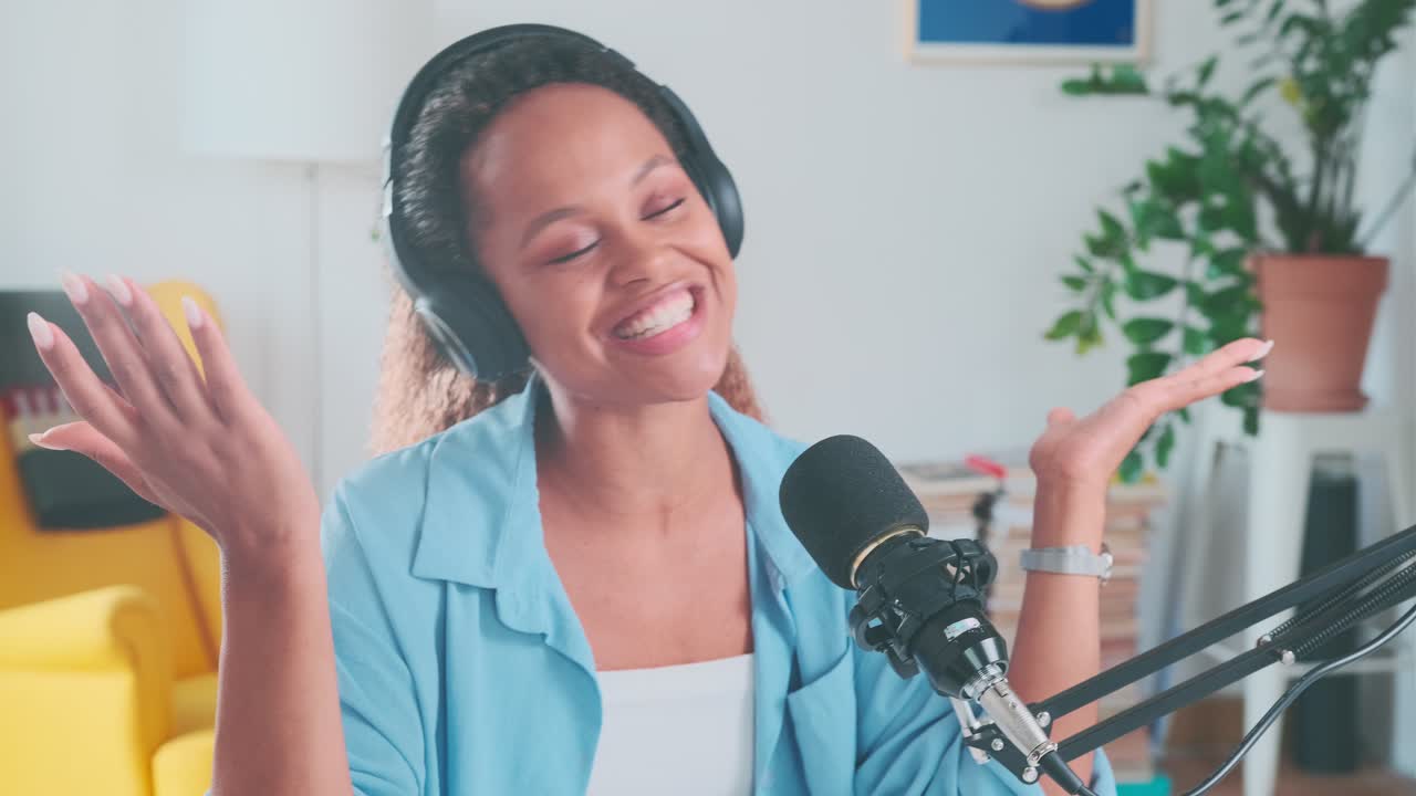 Young cheerful african american woman radio host in headphones waves hands