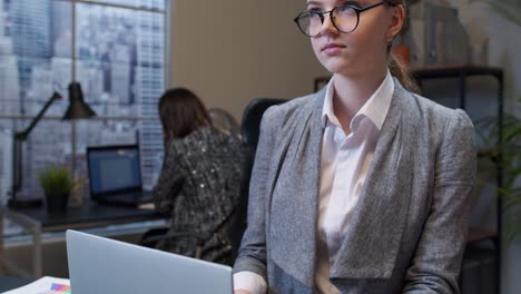 Thoughtful-young-business-woman-working-on-laptop-in-office-wondering-difficult-solution,-imagining