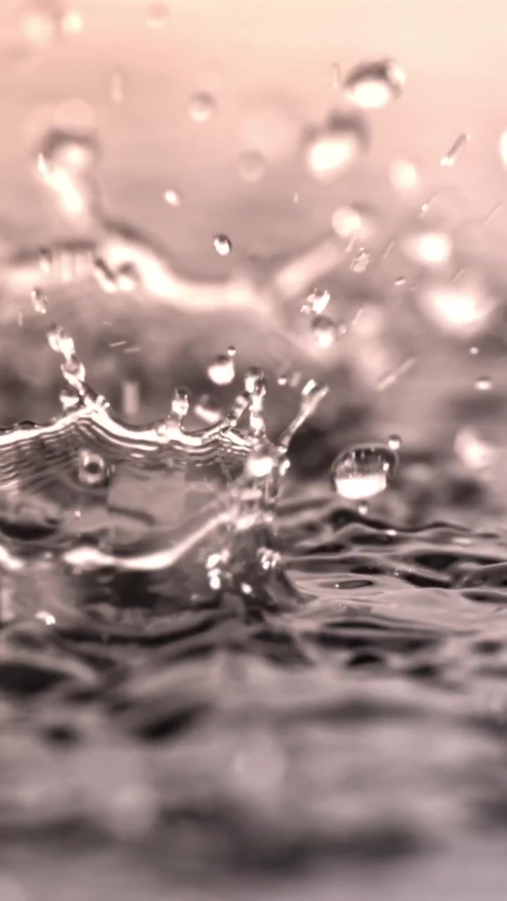 Primo piano al rallentatore di gocce d'acqua che schizzano su una superficie liquida