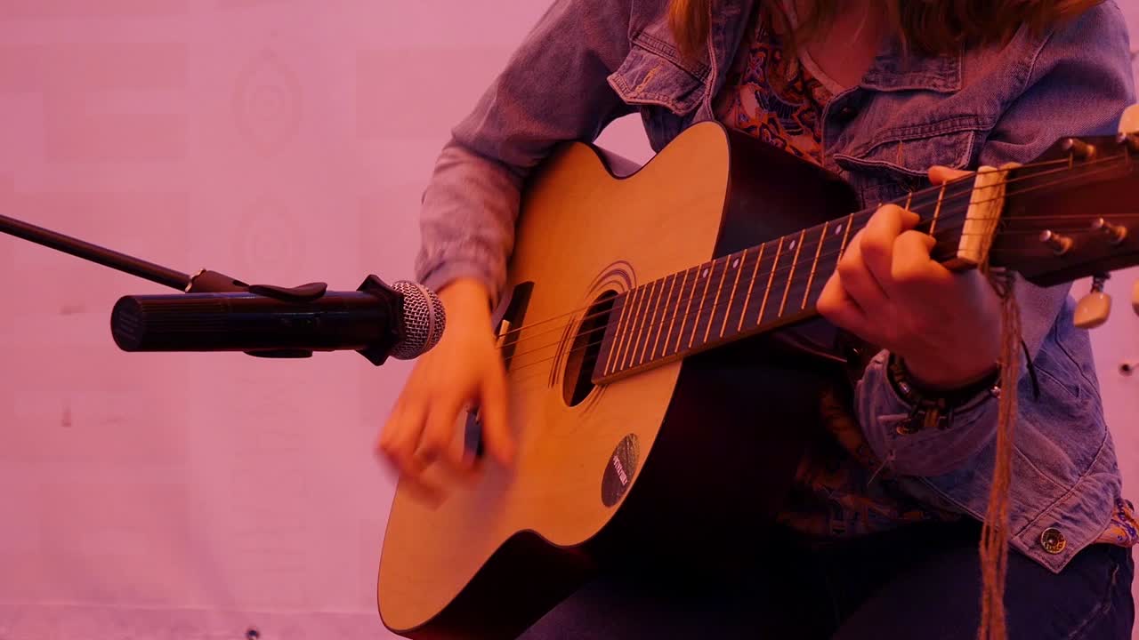 Ung kvinde spiller akustisk guitar