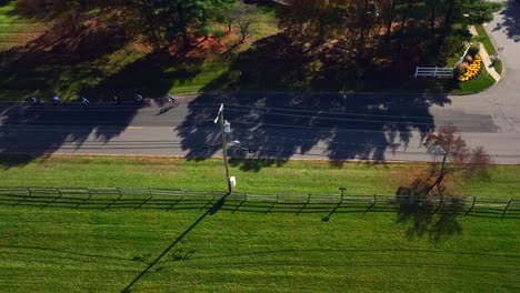 An-aerial-view-of-a-two-lane-road-with-green-fields-and-colorful-trees-on-a-sunny-day-in-autumn