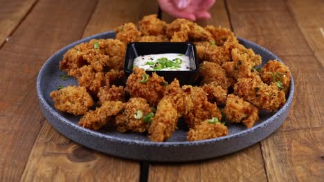 closeup of hand dipping a piece of chicken into a ranch dip