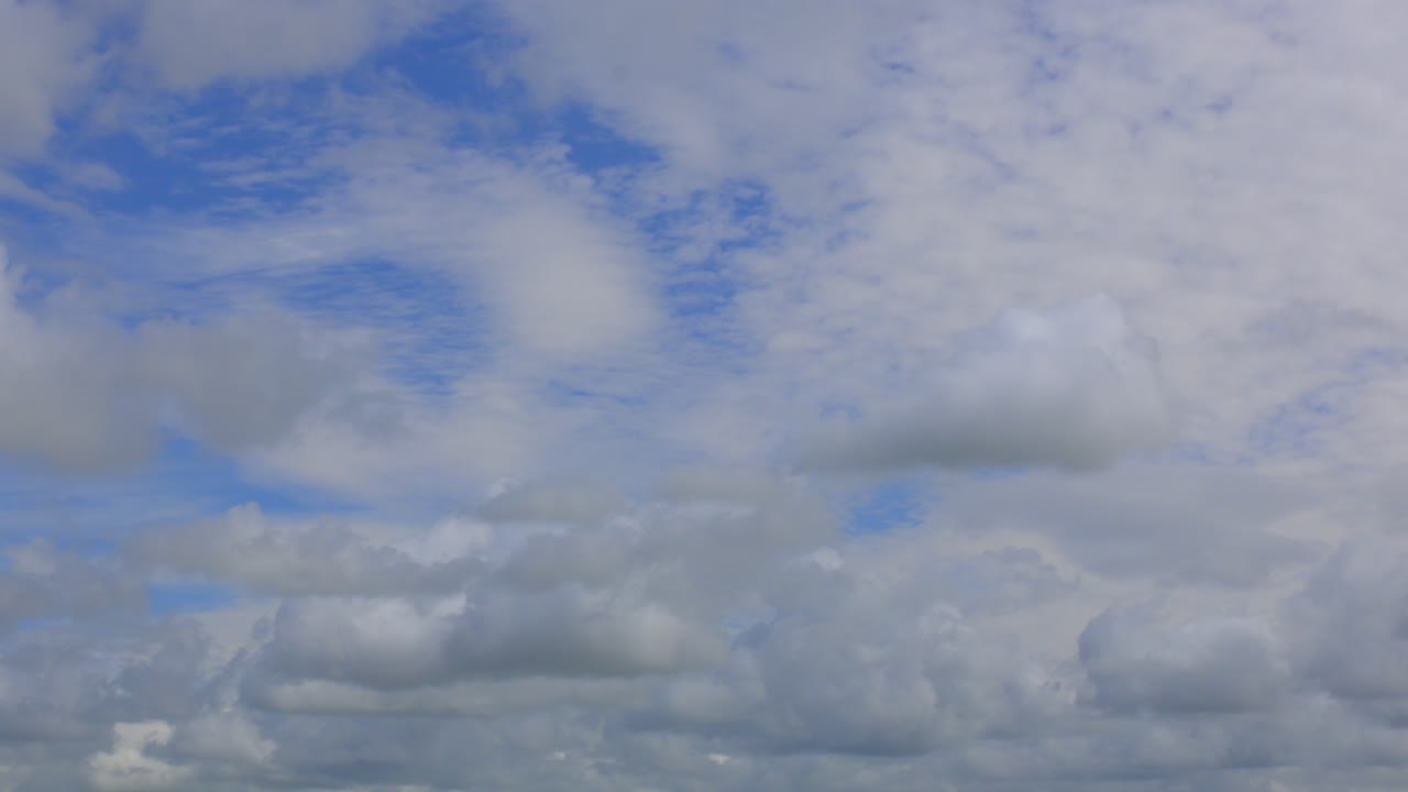 빛나는  ⁇ 은 여름날에 다른 방향으로 움직이는 더 높은 구름과 함께  ⁇ 색 구름이 날아가고 있습니다.