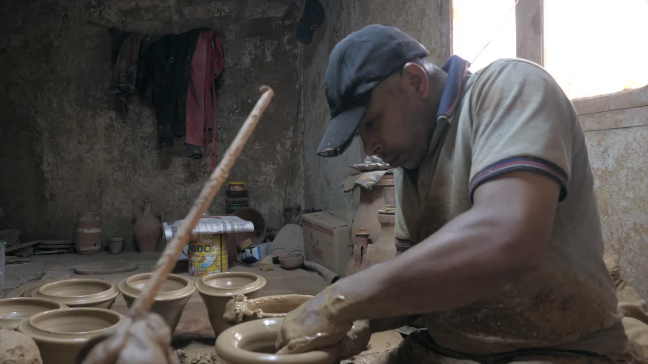 Side view of potter making and shaping clay vessel rotating on potters wheel