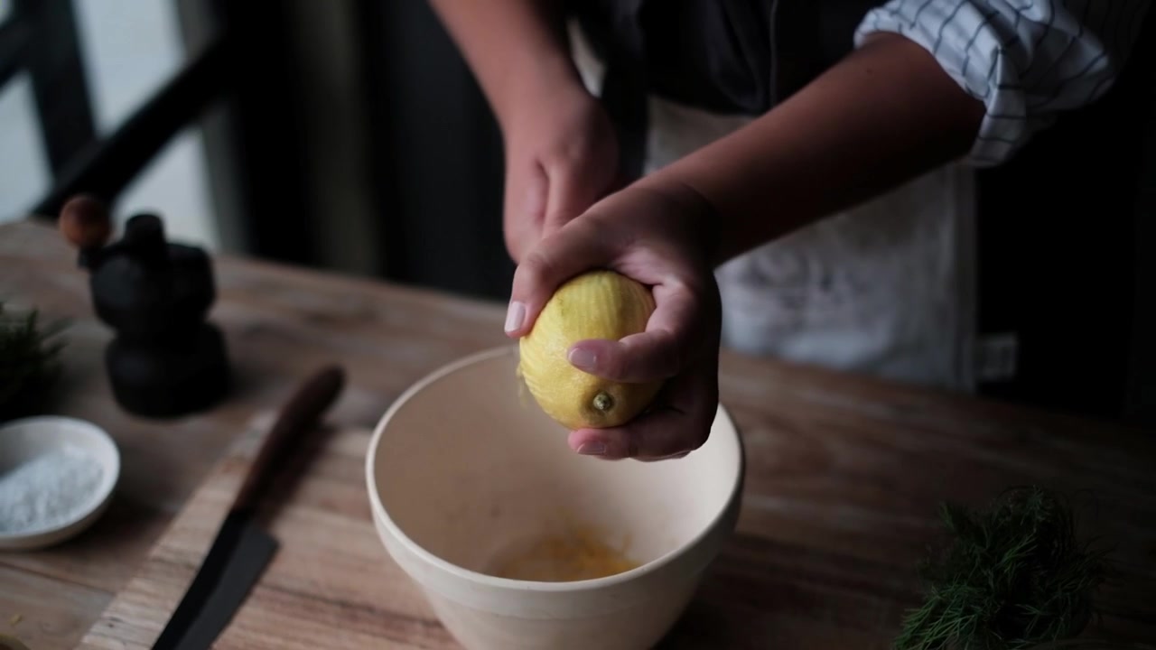 Rallando la cáscara de un limón a mano en un ambiente con poca luz