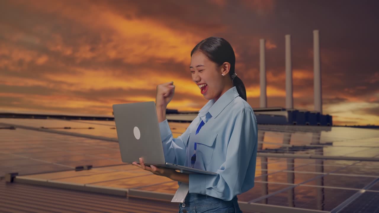 日落時分，一名亞洲女性在屋頂上，手持手提電腦檢查太陽能電池板。她在手提電腦上輸入後，興奮地舉起拳頭高呼成功。
