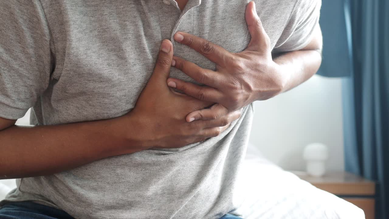 Young man suffering pain in heart and holding chest with hand