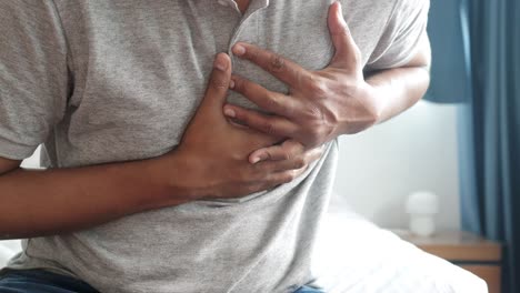 young man suffering pain in heart and holding chest with hand