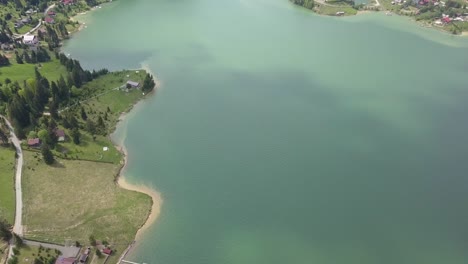 aerial high altitude shot of lake - reservoir front where water meets land with clear water and roads