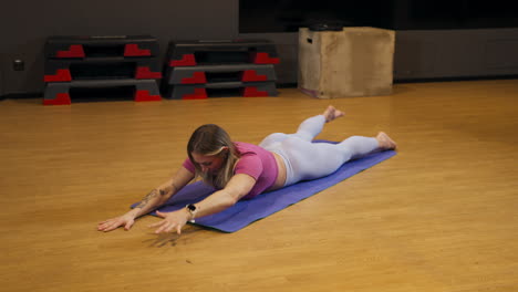 strong tattooed model doing gluteus exercises on a mat at the gym