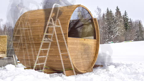 people building wooden barrel sauna during wintertime