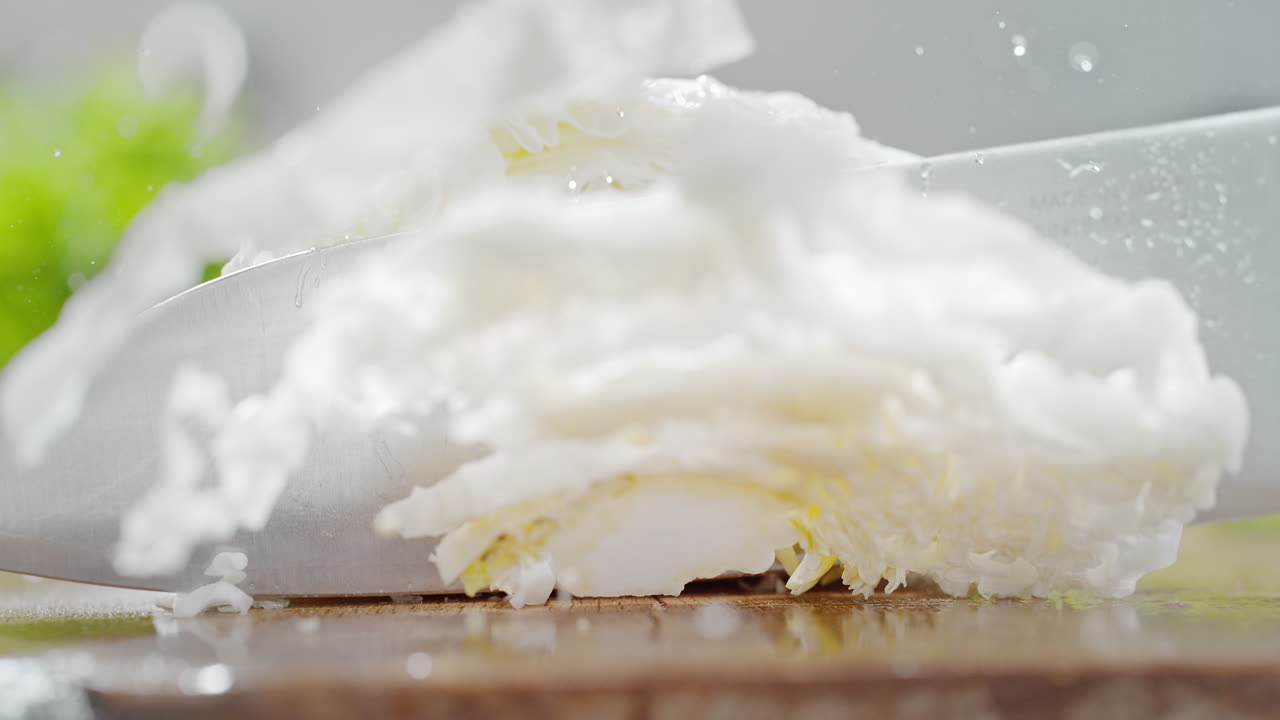 Cutting Chinese Cabbage With A Sharp Knife On A Wooden Water Covered Cutting Board in Macro and Slow Motion