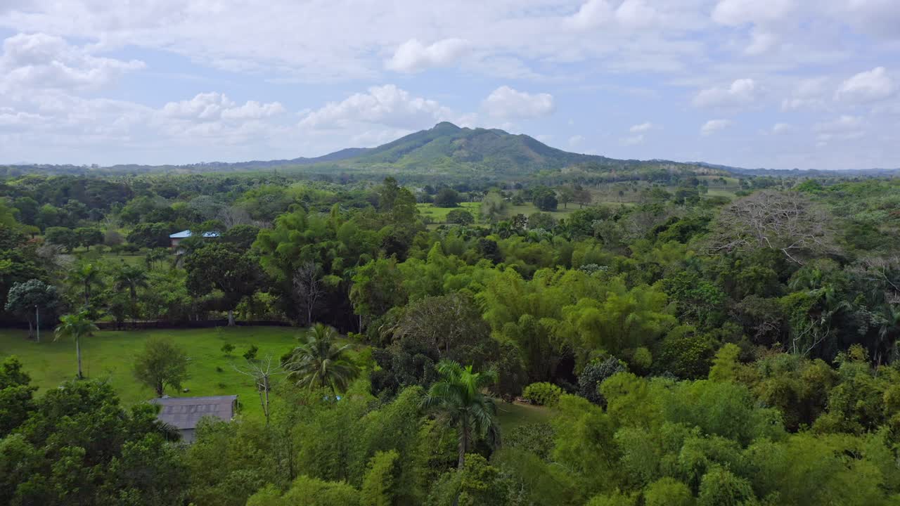 Aerial forward flight over tropical scenery of Bayaguana and mountain in background