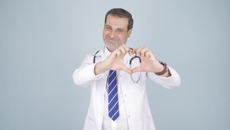 el médico hace el corazón mirando a la cámara.