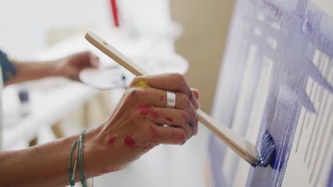 Video-of-hands-of-biracial-female-artist-painting-in-studio