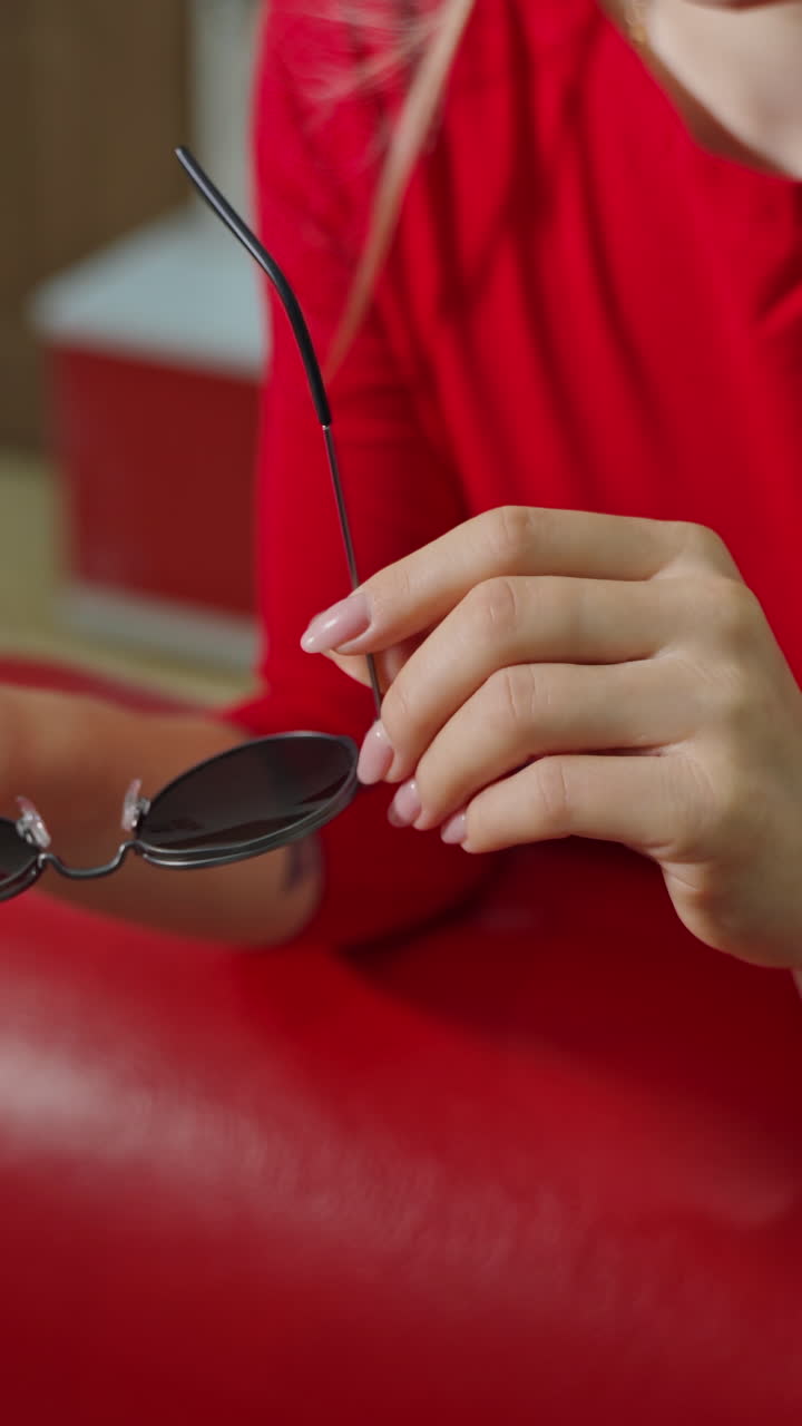 Woman buying sunglasses in shop. Close up of woman in optician store holding stylish sunglasses