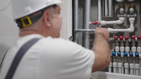 plumber carries out work in the house and opens the water in the water distribution panel