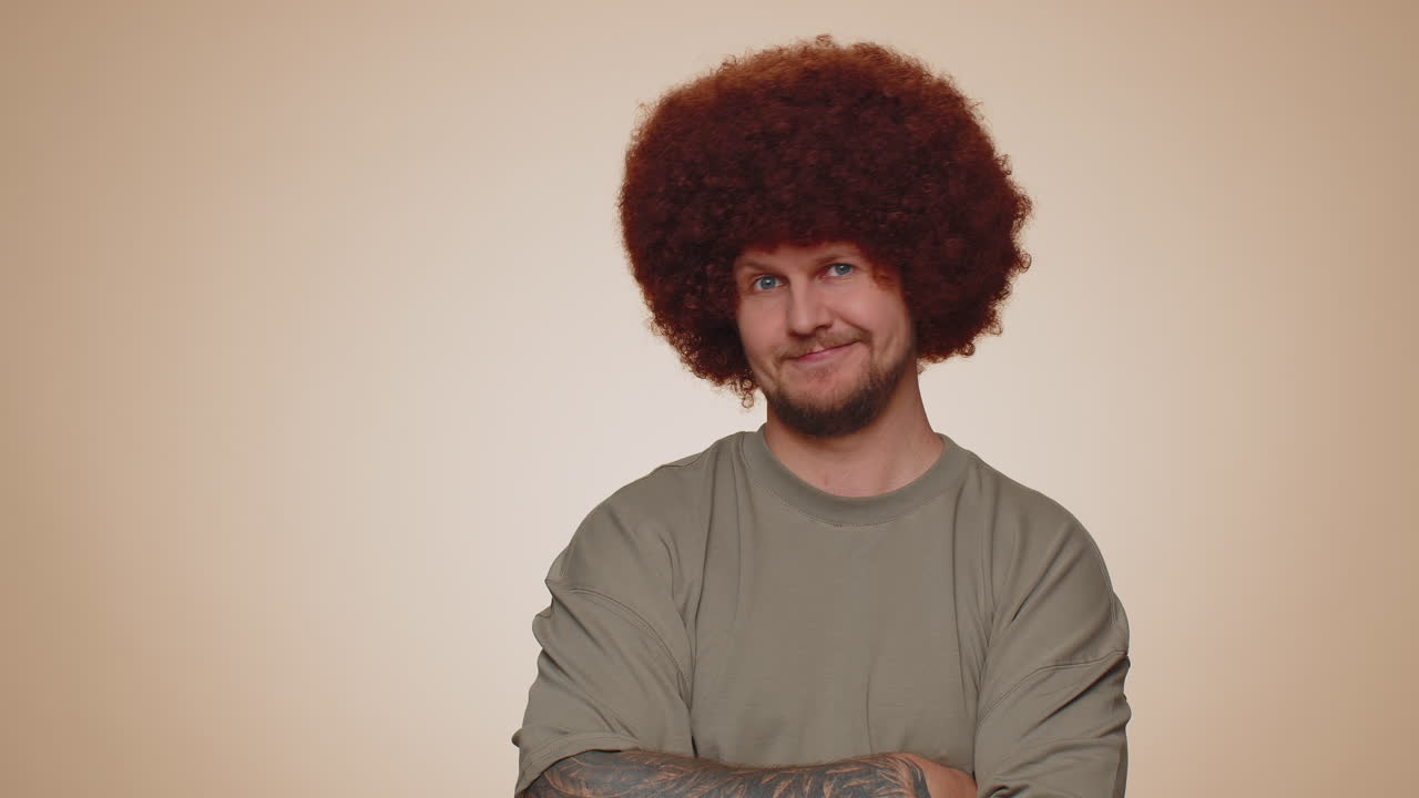 joven adulto barbudo alegre y encantador modelo de moda en camiseta sonriendo y mirando a la cámara solo