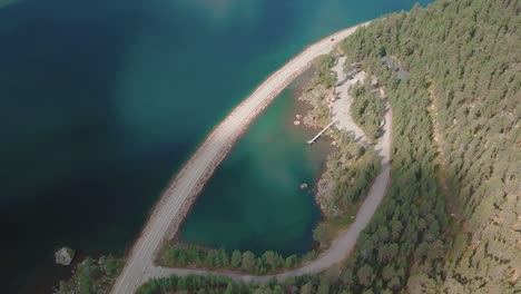 Crane-down-forward-aerial-shot-of-a-road-that-passes-over-a-lake-in-Lapland