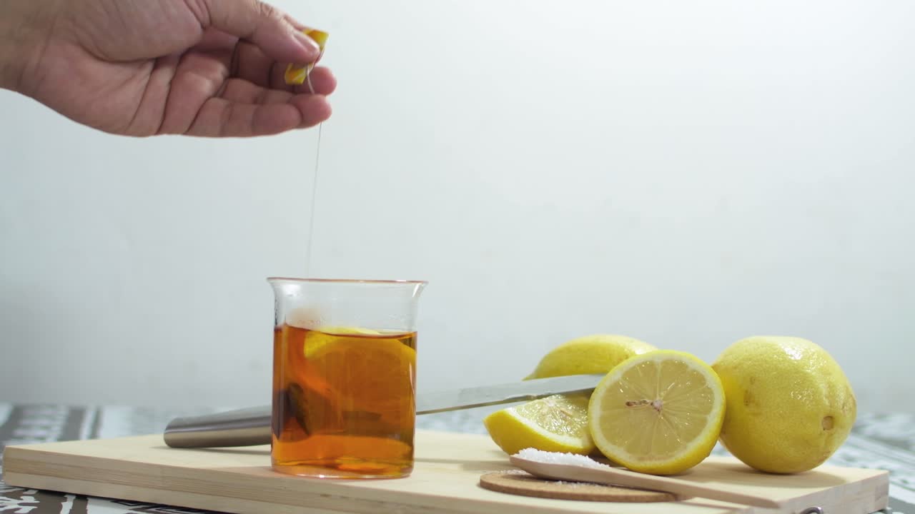 Preparing green tea with lemon wedges. On wooden cutting board.