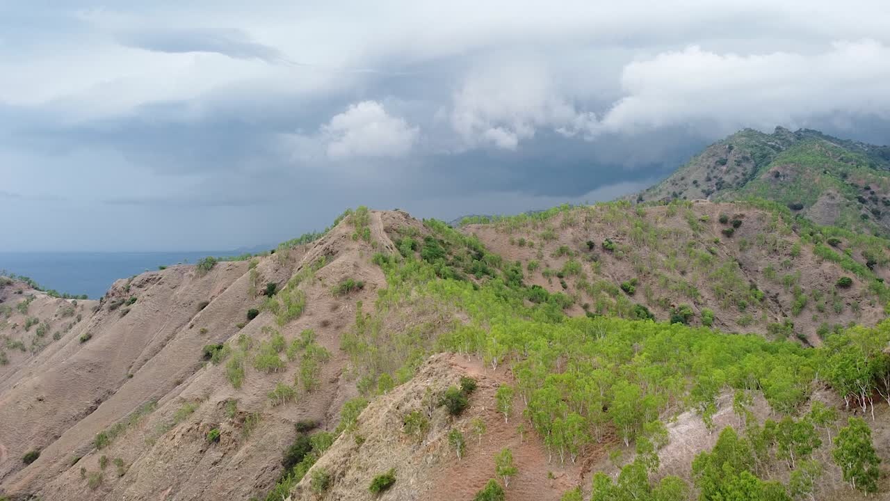 Che si erge su vaste catene montuose rocciose con scarsa vegetazione, alberi e piante durante la stagione secca su un'isola tropicale remota