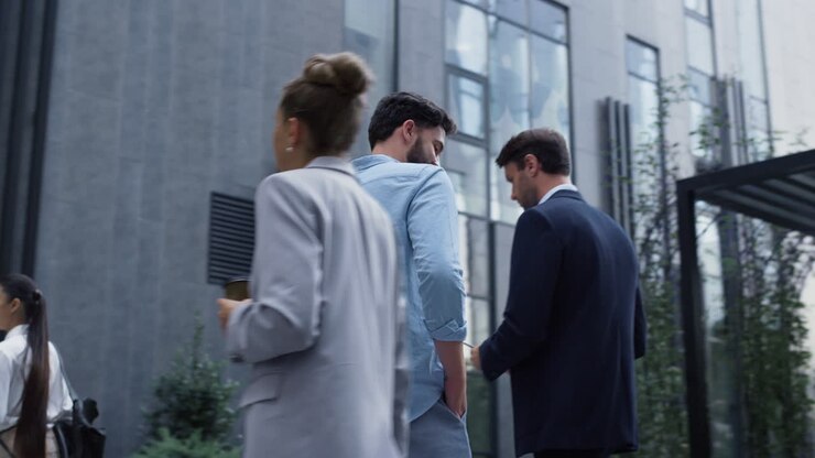 Uomo sicuro di sé che parla al telefono nella zona centrale. Diverse persone d'affari che camminano.