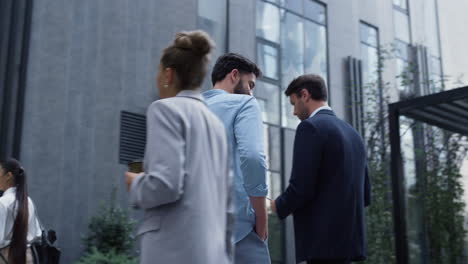 confident man speaking phone at downtown area. various corporate people walking.