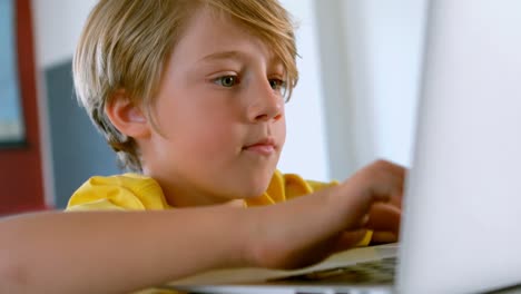 Cute-Caucasian-schoolboy-sitting-at-desk-and-using-laptop-in-classroom-4k