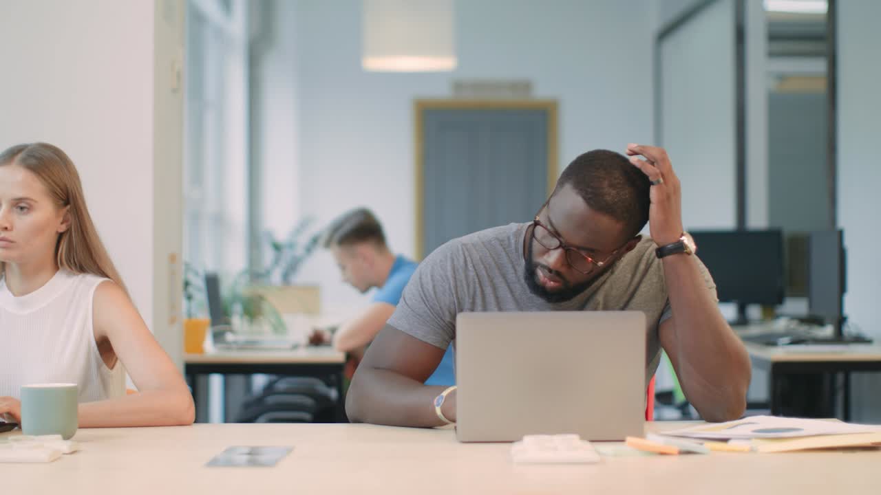 Concentrated man working laptop compute. Black male receiving unexpected letter.
