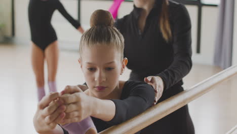 close up view of a gymnastic blonde girl rehearsing a posture at the ballet barre