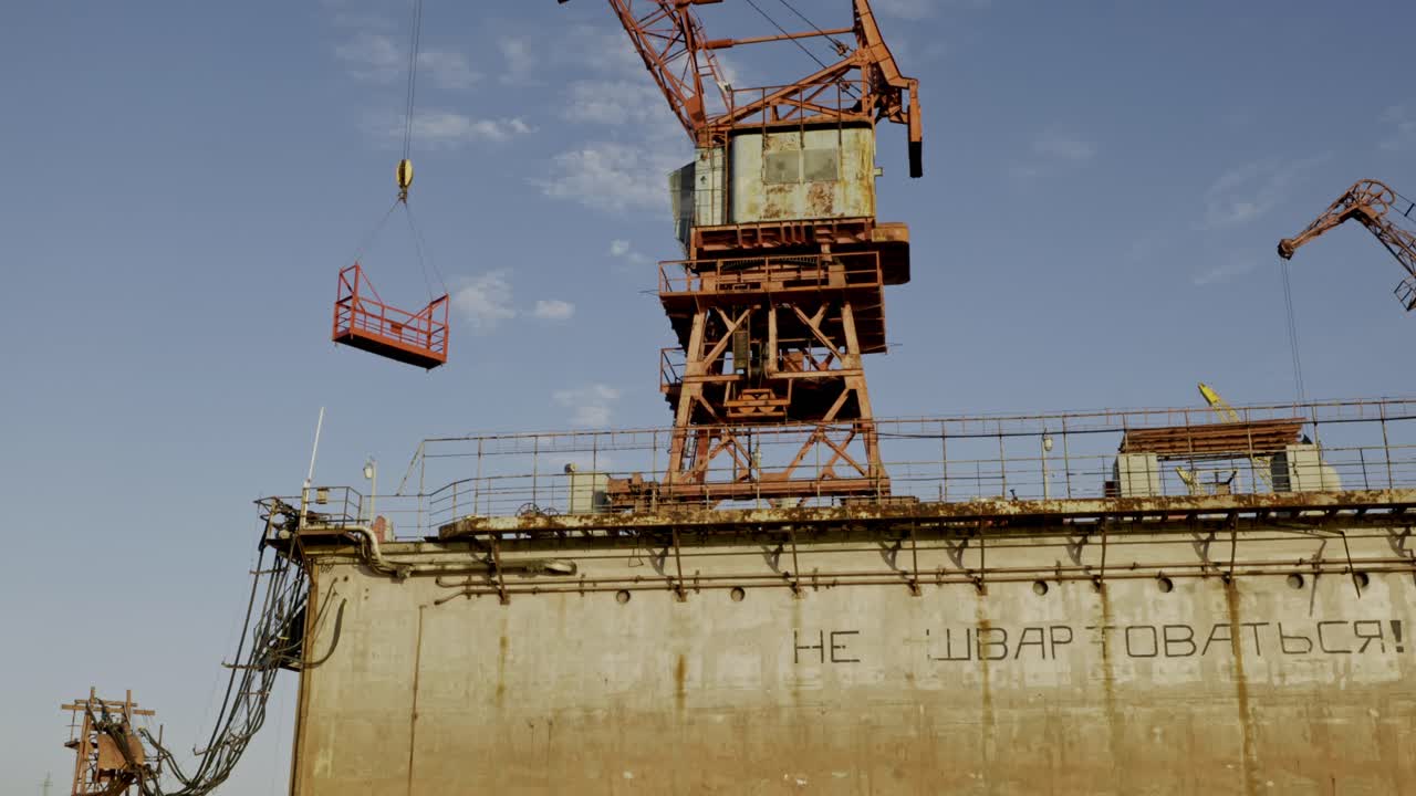 Old Soviet industrial site with crane and faded Russian inscription on the wall