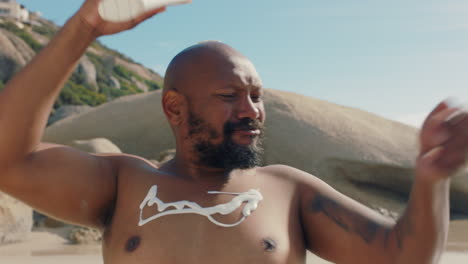 hombre gracioso con sobrepeso en la playa aplicando loción de bronceado en el cuerpo sonriendo emocionado por el día de verano protector solar cuidado de la piel protección 4k