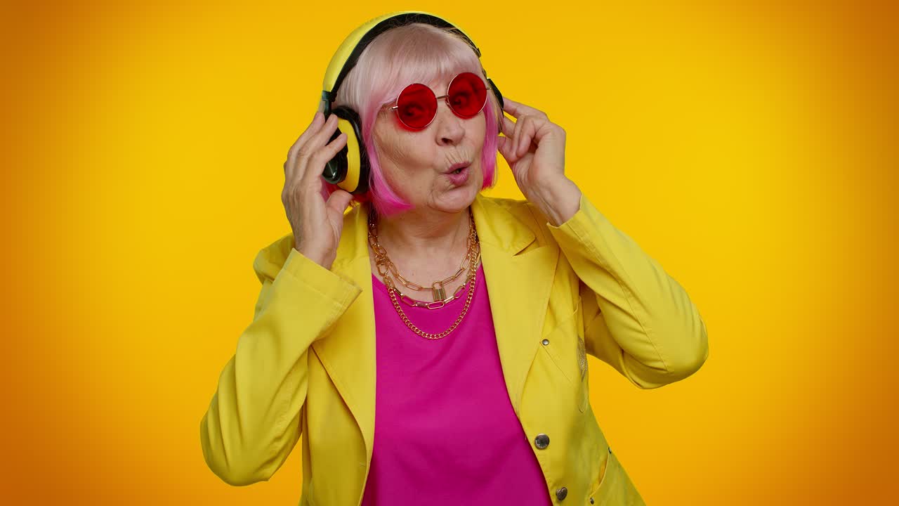 mujer mayor escuchando música en auriculares bailando discoteca engañando, divirtiéndose, gesticulando las manos